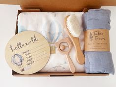 a wooden brush, toothbrush, towel and other items in a cardboard box on a white surface