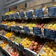 an assortment of fruits and vegetables on display in a grocery store with price tags attached to the shelves