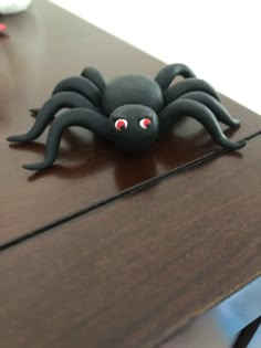 a black spider sitting on top of a wooden table