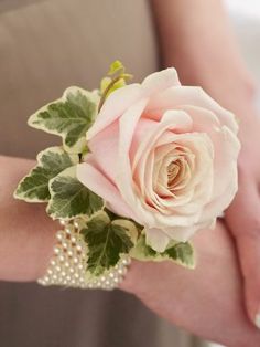 a woman's arm with a pink rose and pearls bracelet on top of it