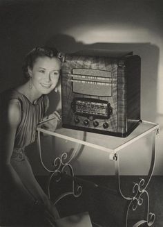 a woman sitting in front of an old fashioned radio