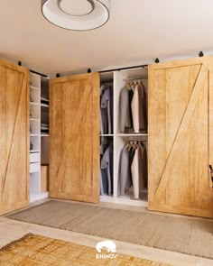 an open closet with wooden doors and clothes hanging on the walls, in front of a beige rug