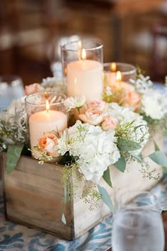 a wooden box filled with white and pink flowers on top of a blue table cloth