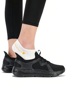 a woman's feet wearing black and white sneakers with yellow accents on the soles