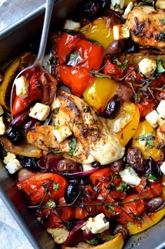 a pan filled with chicken and vegetables on top of a table next to a fork