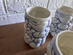 three blue and white vases sitting on top of a wooden table next to each other