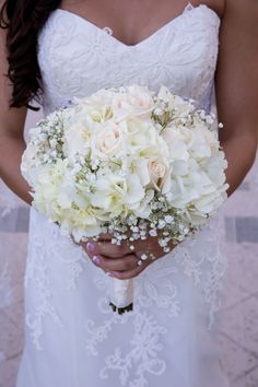 a bride holding a bouquet of white flowers