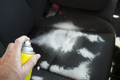 someone sprays down the interior of their car with a yellow bottle and black seat