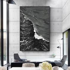 a black and white painting hanging on the wall above a dining room table with chairs