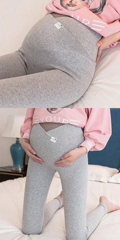 the pregnant woman is laying on her stomach and wearing grey pants with pink hoodie