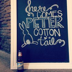 there is a sign that says here comes peter cotton and tails on the wall next to a beer bottle