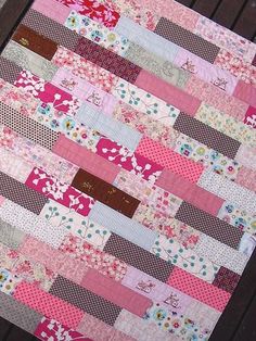 a pink and brown quilt sitting on top of a wooden bench