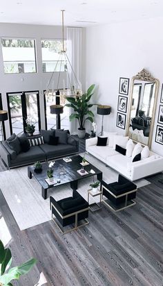 a living room filled with black and white furniture next to a large mirror on the wall