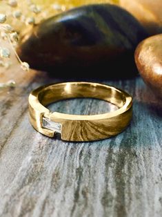 a gold ring sitting on top of a wooden table next to some rocks and stones