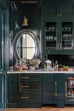 a kitchen with green cabinets and marble counter tops, gold trim around the cabinet doors