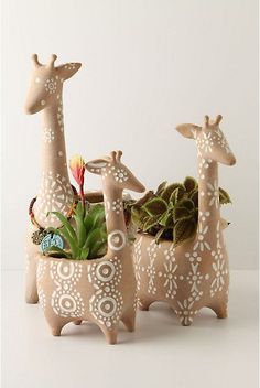 three ceramic giraffe planters with succulents in them