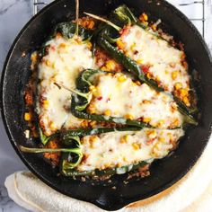 a skillet filled with green beans and cheese covered in sauce on top of a white towel