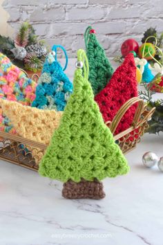 crocheted christmas tree ornaments in a basket on a marble counter with other decorations