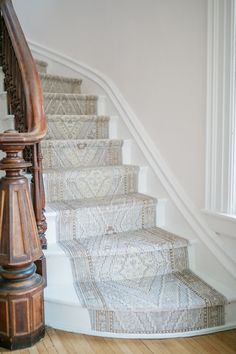 a staircase with wooden handrails and carpeted steps leading up to the second floor