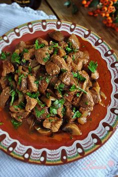 a red plate topped with meat and mushrooms covered in gravy on top of a table