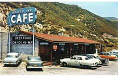 cars parked in front of a cafe on the side of a mountain