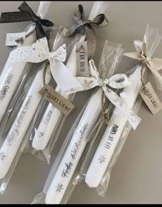 four white candles wrapped in clear cellophane and tied with ribbon, sitting next to each other