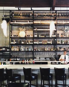 a man sitting at a bar with lots of bottles on the wall behind him,