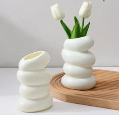 two white vases with tulips in them on a wooden tray next to each other