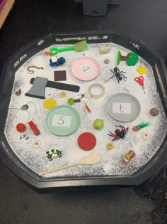 a sand tray filled with different types of toys on top of a black countertop