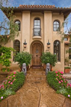 the front entrance to a house with flowers and plants on the steps leading up to it