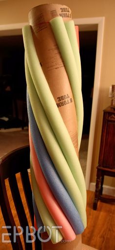 a stack of multicolored paper sitting on top of a wooden table next to a chair