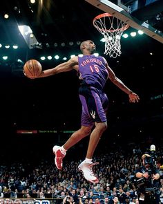 a basketball player jumping up into the air to dunk a ball in front of an audience