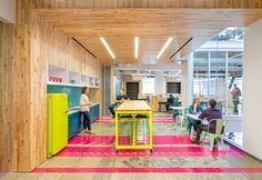 people sitting at tables in an office with colorful flooring and wood paneled walls