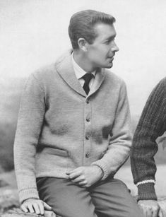 black and white photograph of two men sitting next to each other, one wearing a sweater