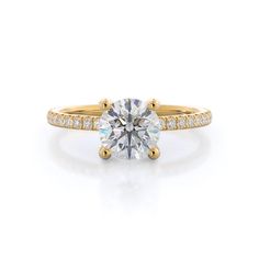 a yellow gold engagement ring with a round cut diamond in the center and pave set shoulders