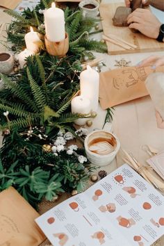 a table topped with lots of different types of candles and paper on top of it