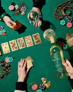 people playing cards and drinking wine on a green table with casino chips, dices, and other items