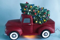 an old red truck with a christmas tree on the back and lights in the bed