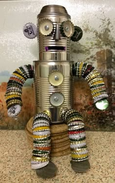 a metal robot sitting on top of a table next to a wall covered in magnets