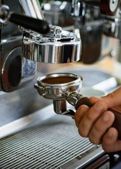 a person is filling a cup with coffee from a machine in a restaurant or bar