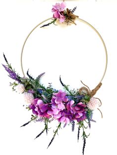 a wreath with purple flowers and greenery hanging from the side on a white background