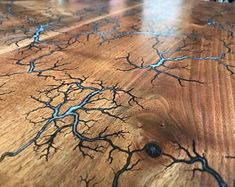 a wooden table with blue and black lines on the wood grained surface that looks like tree branches