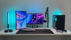 three computer monitors sitting on top of a desk next to a keyboard and monitor screen