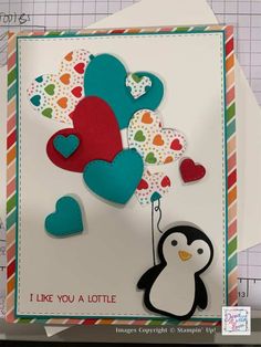 a card with a penguin and heart balloons