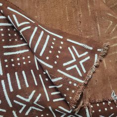 two brown and white patterned blankets on top of each other, one with fringes