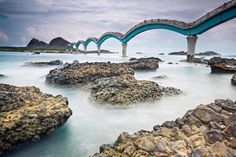 a bridge that is over some rocks in the water