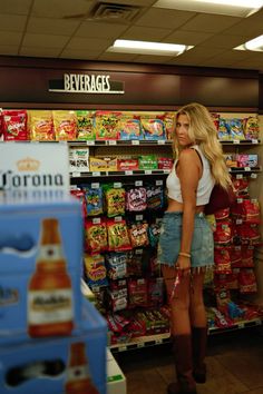 a woman standing in front of a store display filled with drinks and snacks for sale