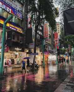 people are walking down the street in the rain