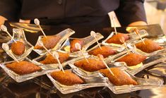 small appetizers are arranged in clear dishes on a glass platter with toothpicks sticking out of them