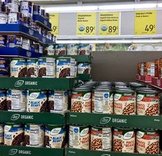 an assortment of canned beans and other foods on display in a grocery store's produce section